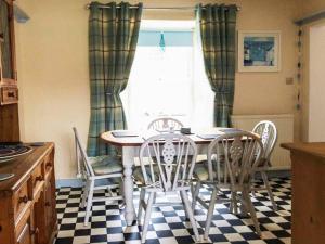 a kitchen with a table and chairs and a window at Dermot Cottage in Gatehouse of Fleet