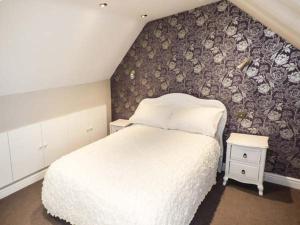 a bedroom with a white bed and a floral wall at Sea View Apartment in Llanfairfechan