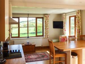 a living room with a dining table and a large window at Glebe Farm Cottage in Pontnewydd