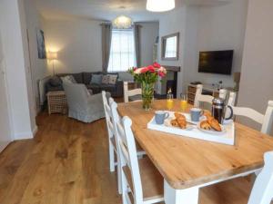a dining room with a wooden table with flowers on it at Silversands Cottage in Amble