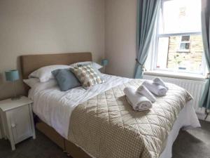 een slaapkamer met een bed met handdoeken erop bij Silversands Cottage in Amble