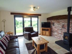 a living room with a couch and a brick fireplace at Tyn Y Celyn Uchaf in Clocaenog