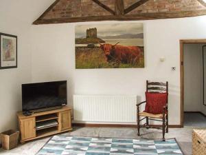 una sala de estar con TV y una vaca en la pared en Finwood Cottage 1 en Rowington