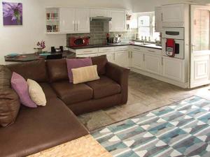 a living room with a brown couch and a kitchen at Finwood Cottage 1 in Rowington