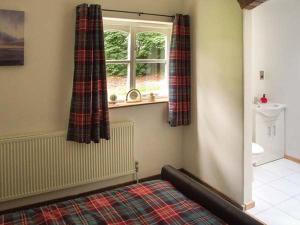 een slaapkamer met een bed en een raam met gordijnen bij Finwood Cottage 1 in Rowington