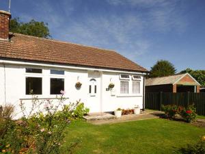 a white house with a grass yard in front of it at Spurling Cottage in Cheveley