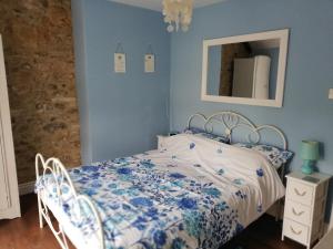 a blue bedroom with a bed and a mirror at St Margaret's Cottage in Chardstock
