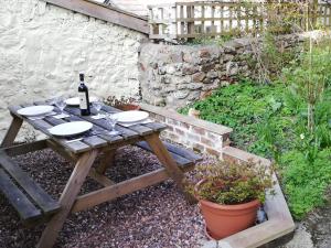 a wooden picnic table with a bottle of wine on it at St Margaret's Cottage in Chardstock