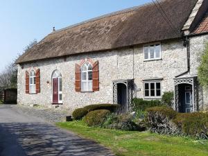 an old stone house with a thatched roof at St Margaret's Cottage in Chardstock