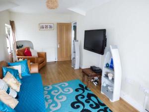 a living room with a blue couch and a tv at Ty'r Enfys Bach - Upper in Trearddur
