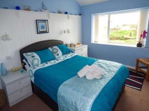 a blue bedroom with a bed with towels on it at Ty'r Enfys Bach - Upper in Trearddur