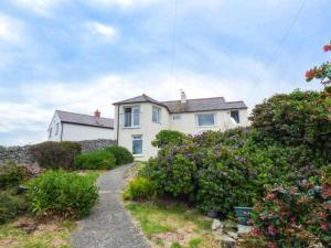 a white house with a path leading to it at Ty'r Enfys Bach - Upper in Trearddur