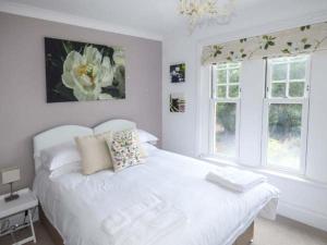 a white bedroom with a white bed and two windows at 4 The Nab House in Bembridge