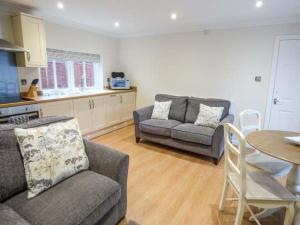 a living room with two couches and a table and a kitchen at Walworth Castle Holiday Cottage in Walworth