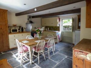 a kitchen with a wooden table and chairs in a kitchen at Ploony Cottage in Bleddfa