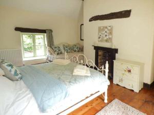 a bedroom with a white bed and a fireplace at Ploony Cottage in Bleddfa