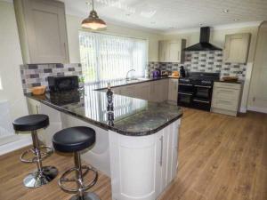 a kitchen with a counter and two bar stools at Bryn Tirion in Bettws-yn-Rhôs