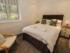 a bedroom with a bed and a chair and a window at Thompson Cottage in Troutbeck