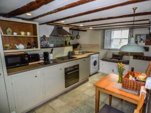 ミドルハムにあるCastle Hill Cottageの白いキャビネットとテーブル付きのキッチンが備わります。