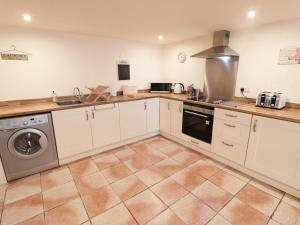 a kitchen with white cabinets and a washer and dryer at The Nook at Timbers in Great Longstone