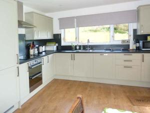 a kitchen with white cabinets and a wooden floor at Fronthill in Newtonmore