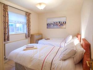 a bedroom with two beds and a window at Ty Woods Cottage in Rhoscolyn +1 photo