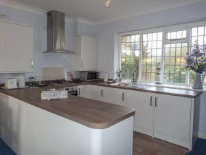 uma cozinha com armários brancos e um balcão de madeira em Herbrand House em Bexhill