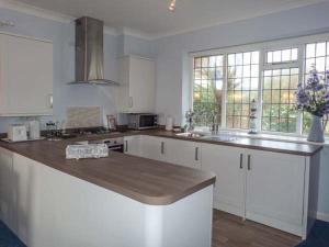 Una cocina con gabinetes blancos y una encimera de madera. en Herbrand House, en Bexhill-on-Sea