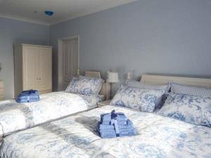 a bedroom with two beds with blue and white pillows at Herbrand House in Bexhill