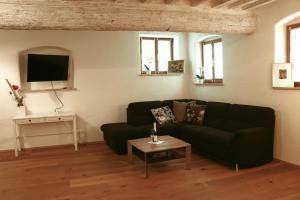 a living room with a black couch and a table at Stilvolle Wohnung auf 50 m² mit Parkplatz und WiFi in Kraiburg am Inn