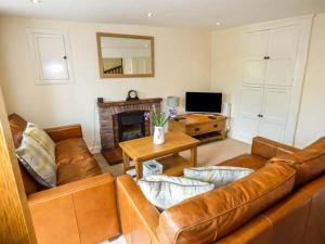 un soggiorno con divano e tavolo di Cinderbarrow Cottage a Levens