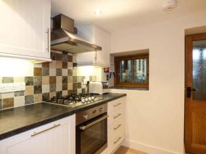 una cucina con mobili bianchi e un forno a piano cottura di Cinderbarrow Cottage a Levens Altre 7 foto