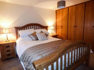 Cinderbarrow Cottage في Levens: غرفة نوم بسرير خشبي كبير مع مواقف ليلتين