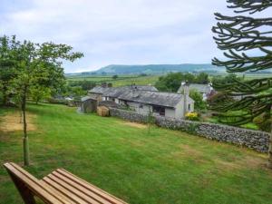 una panchina da parco seduta in un campo con una casa di Cinderbarrow Cottage a Levens