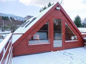 a red cabin with a snow covered roof at Strathavon Chalet in Aviemore