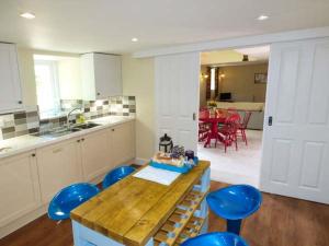 a kitchen with a wooden table and blue stools at Vale Barn in Dronfield