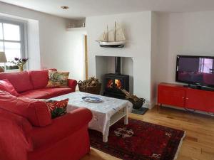 a living room with a red couch and a fireplace at Fish House in Kirkcudbright