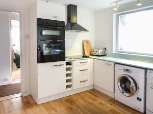 a kitchen with white cabinets and a washer and dryer at Fish House in Kirkcudbright