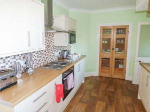 a kitchen with white cabinets and a wooden floor at Mayfield Manor in Whitby