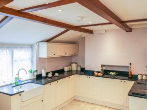 a kitchen with white cabinets and black counter tops at 3 Old Police Station in Dunster