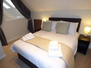 a bedroom with a large white bed with two pillows at Shepherd Oak in Broadwey
