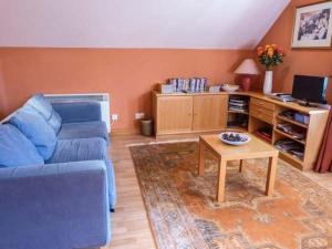 a living room with a blue couch and a table at Stemster School House Apartment in Castletown