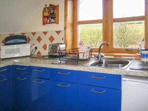 a kitchen with blue cabinets and a sink and a window at Stemster School House Apartment in Castletown