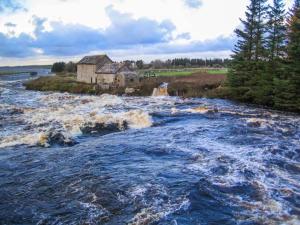 a river with a house in the middle of it at Stemster School House Apartment in Castletown