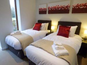 two beds in a hotel room with red pillows at Budmouth in Broadwey