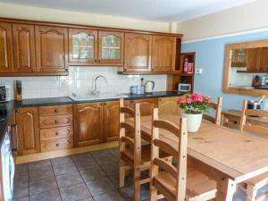 a kitchen with wooden cabinets and a wooden table at Deskford Cottage in Balblair
