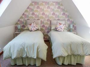 two twin beds in a room with a wall at Deskford Cottage in Balblair