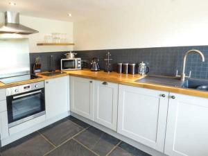 a kitchen with white cabinets and a sink at Fire Brigade Barn in Tissington