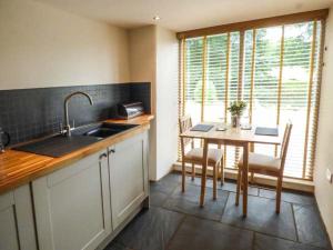 a kitchen with a table and a sink and a table and chairs at Fire Brigade Barn in Tissington