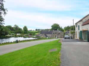 a road in a village with a house and a river at Fire Brigade Barn in Tissington